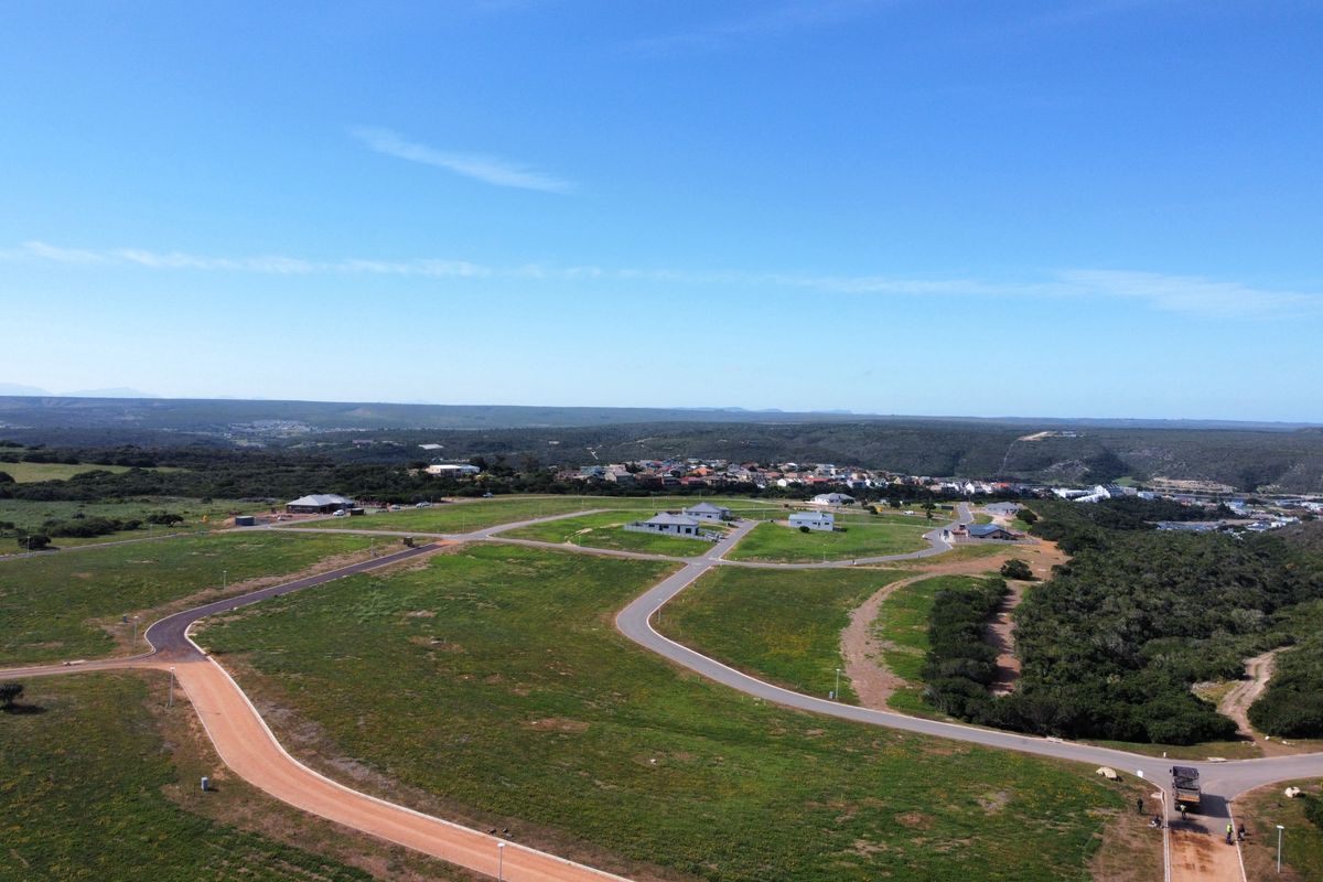 Aerial view of a residential land development featuring established road infrastructure, street lighting, and surrounding natural landscape.