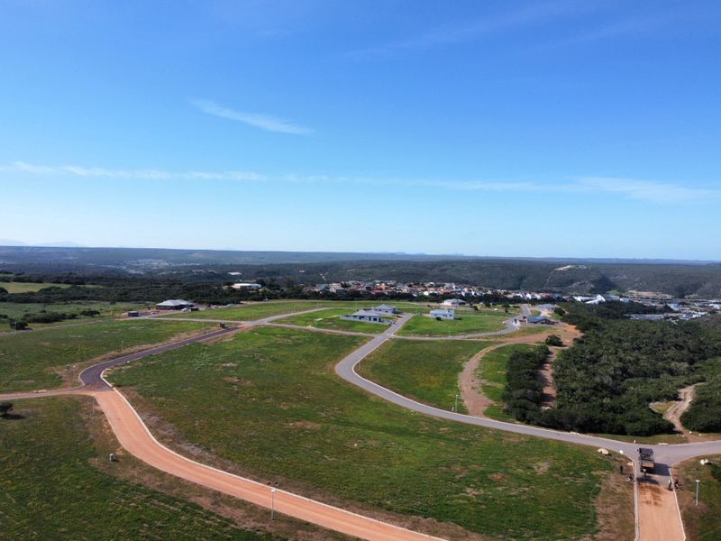 Aerial view of a residential land development featuring established road infrastructure, street lighting, and surrounding natural landscape.
