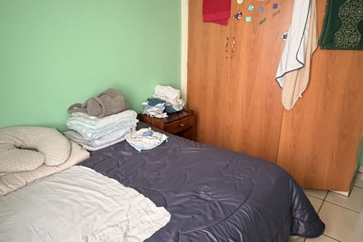 A bedroom featuring built-in wooden cupboards, tiled flooring, and coved ceiling details.