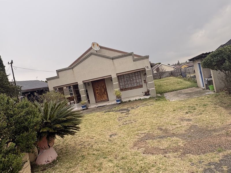 Front view of a single-story residential house featuring a plastered facade, tiled roof, and a paved driveway leading to the entrance.