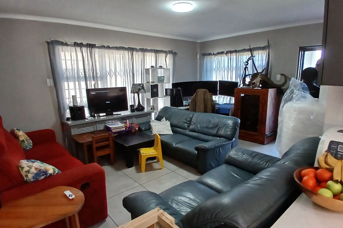 A living room area featuring tiled flooring and security gates on the windows, providing a functional space for relaxation.