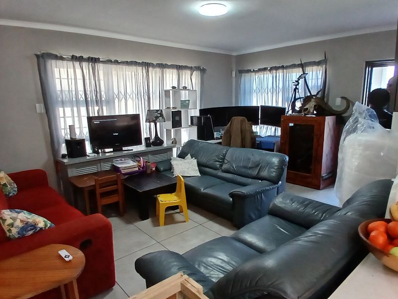 A living room area featuring tiled flooring and security gates on the windows, providing a functional space for relaxation.