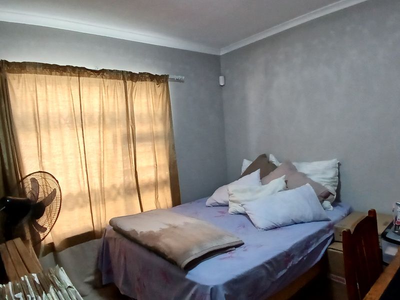 A standard bedroom featuring neutral wall finishes and a window with fitted curtain rods.