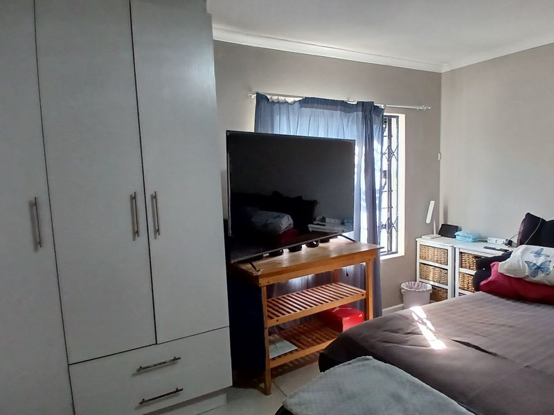 A bedroom featuring a built-in wardrobe, neutral wall finishes, and a window fitted with a security gate.