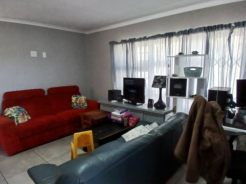 A living room featuring tiled flooring and security bars on the windows, providing a functional space for relaxation.