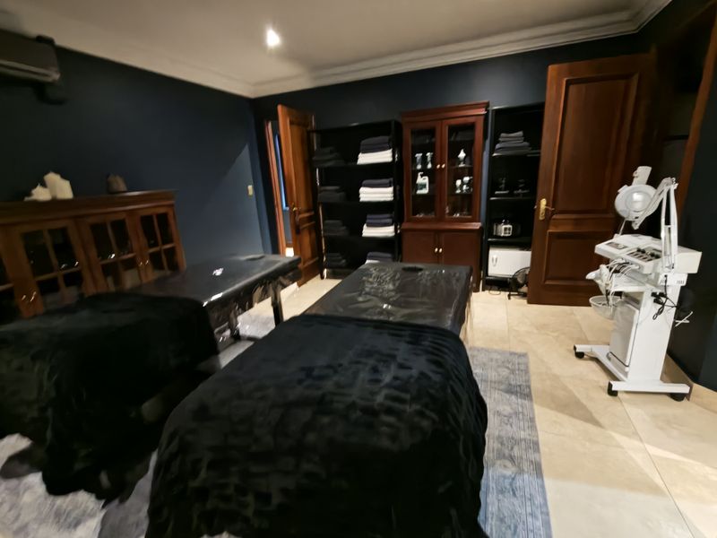 A professional treatment room featuring dark walls, tiled flooring, crown molding, and built-in storage cabinetry, currently set up for spa or clinical services.