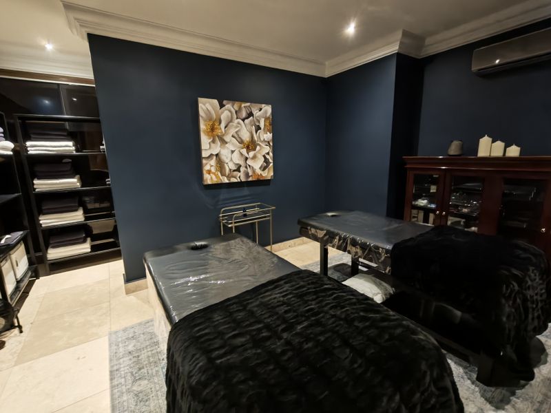 A well-maintained room featuring dark blue walls, crown molding, recessed lighting, and tiled flooring, currently utilized as a professional treatment space.