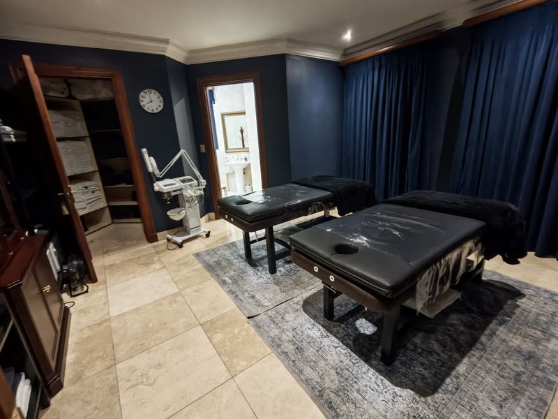 A spacious room currently utilized as a treatment space, featuring stone flooring, crown molding, and an integrated walk-in closet with direct access to an ensuite.