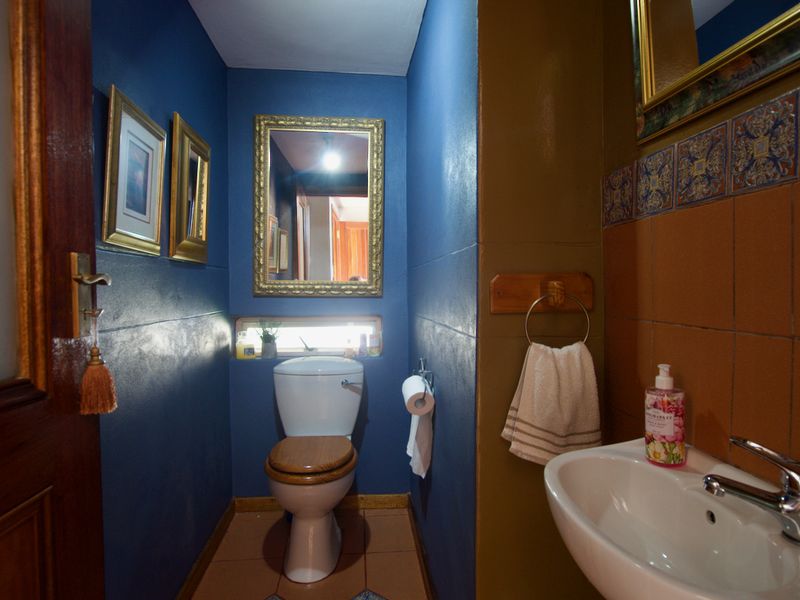 A compact guest bathroom featuring a toilet, wall-mounted washbasin, and decorative tiled accents.