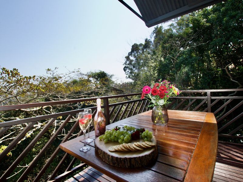 A private balcony featuring timber decking and a wooden balustrade, offering elevated views of the surrounding natural landscape.