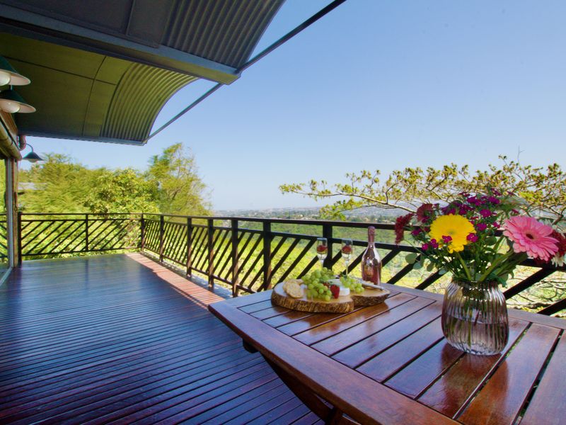 Spacious elevated balcony featuring timber decking, metal balustrades, and a corrugated roof, offering expansive outdoor living space with scenic views.