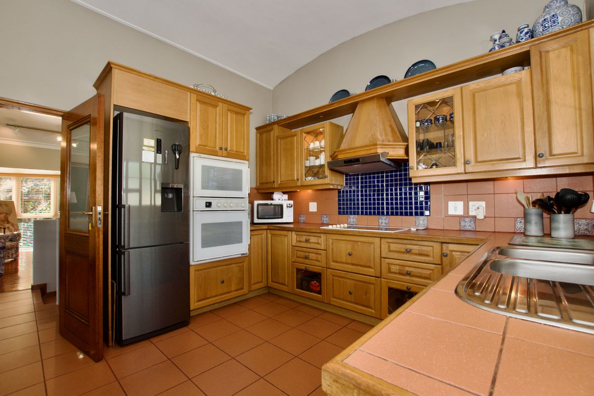 A functional kitchen featuring traditional wooden cabinetry, tiled countertops, a built-in oven, and a tiled backsplash, offering a classic aesthetic with ample storage space.