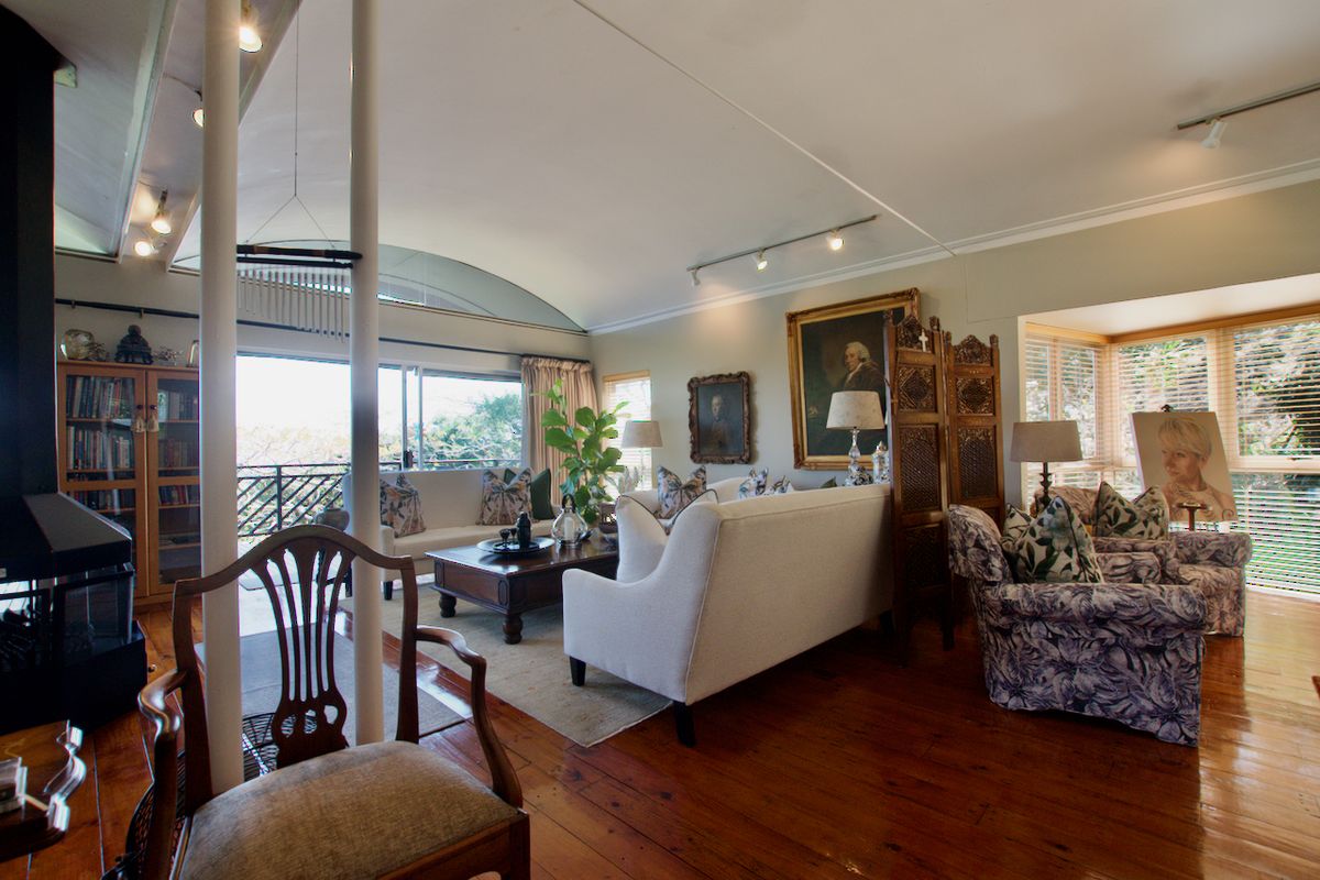 Spacious living room featuring hardwood flooring, a vaulted ceiling, a fireplace, and large sliding glass doors leading to an outdoor area.