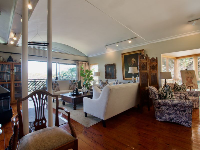 Spacious living room featuring hardwood flooring, a vaulted ceiling, a fireplace, and large sliding glass doors leading to an outdoor area.