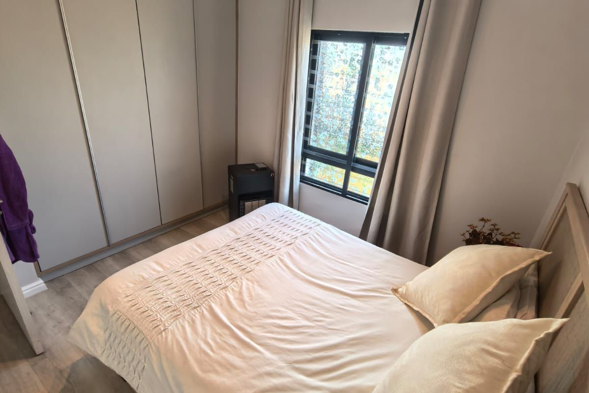 A well-maintained bedroom featuring modern laminate flooring, built-in cupboards, and neutral finishes, offering a clean and comfortable living space.