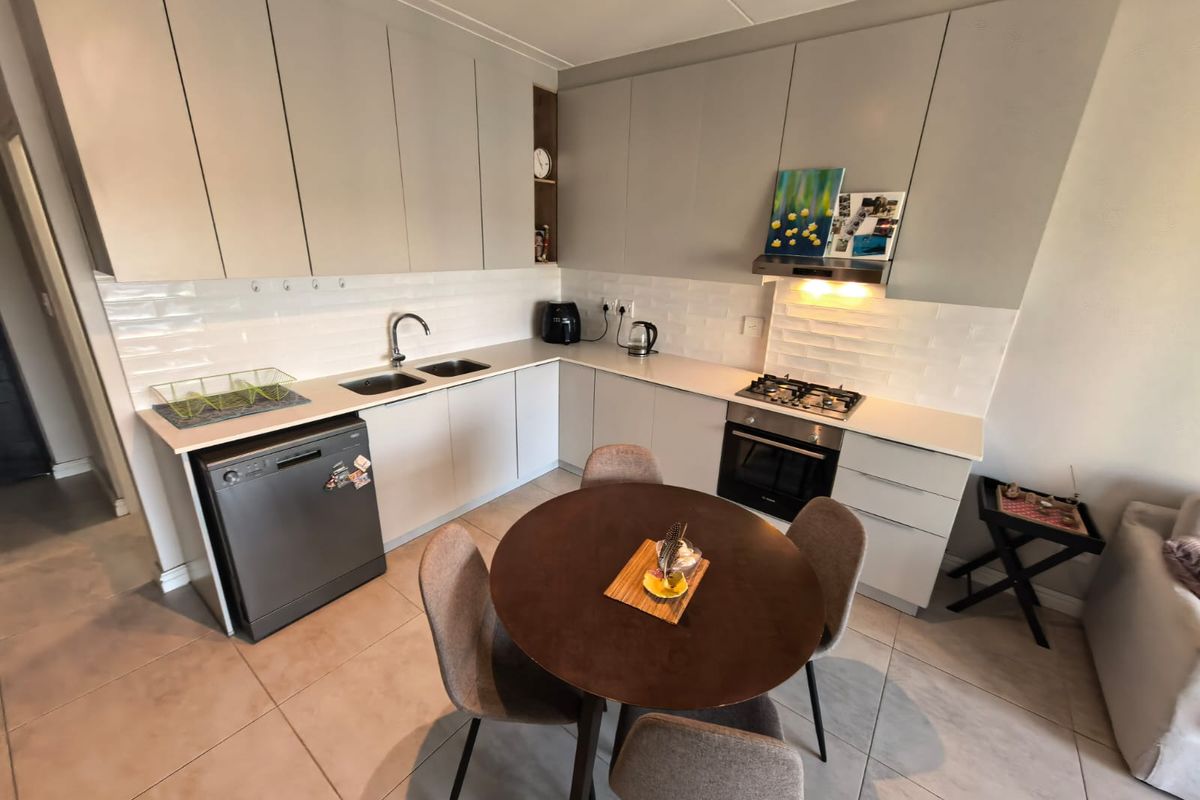 Modern kitchen featuring light grey cabinetry, stone countertops, subway tile backsplash, and integrated stainless steel appliances, complemented by tiled flooring.