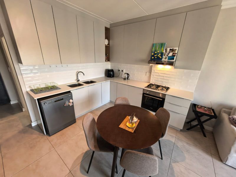 Modern kitchen featuring light grey cabinetry, stone countertops, subway tile backsplash, and integrated stainless steel appliances, complemented by tiled flooring.