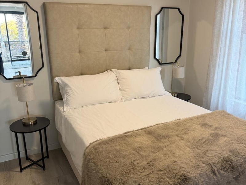 A well-maintained bedroom featuring light-toned laminate flooring and neutral wall finishes, creating a bright and comfortable living space.