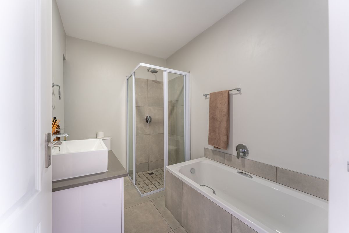 Modern bathroom featuring a separate shower enclosure, a bathtub with tiled surround, and a contemporary vessel sink vanity unit.