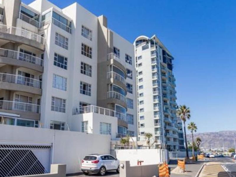 Exterior view of a modern multi-story apartment building featuring balconies and secure perimeter access.