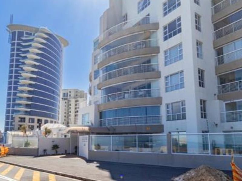 Exterior view of a modern multi-story apartment building featuring glass-fronted balconies and a secure perimeter wall.