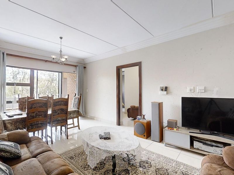 Open plan living and dining area featuring tiled flooring, coved ceilings, and a large sliding glass door providing access to the exterior.