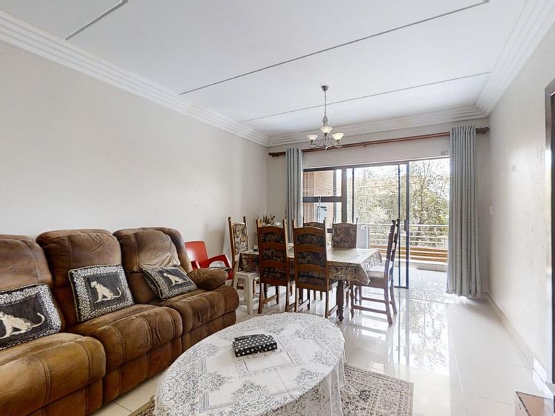 Spacious open-plan living and dining area featuring polished tiled floors, decorative ceiling cornices, and direct access to a private balcony through sliding glass doors.