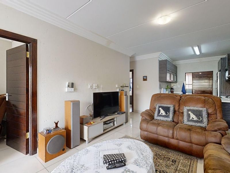 Open-plan living area featuring tiled flooring and a connected kitchen space with built-in cabinetry.
