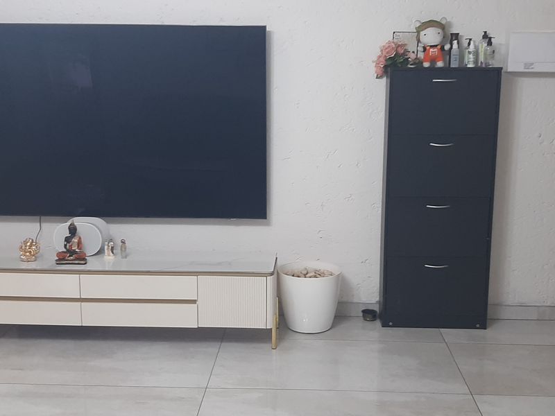 A living room area featuring large format floor tiles and a textured wall finish, providing a neutral backdrop for the space.