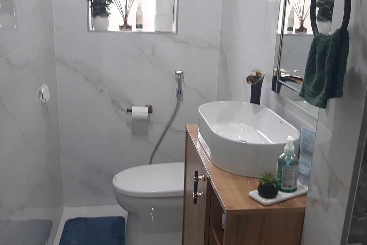 Modern bathroom featuring marble-look wall tiles, a contemporary vessel sink on a wooden vanity, and a glass-enclosed shower.