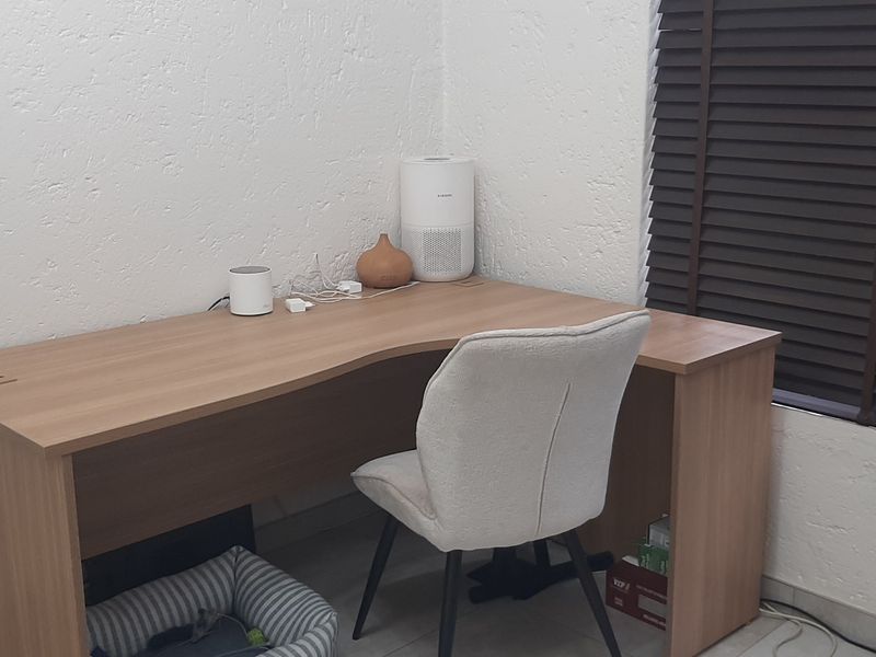 A functional home office space featuring tiled flooring and dark venetian blinds, providing a practical area for work or study.