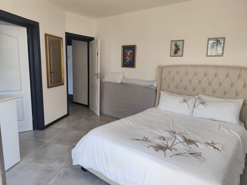 A well-maintained bedroom featuring neutral tiled flooring and classic panel doors, offering a clean and functional living space.