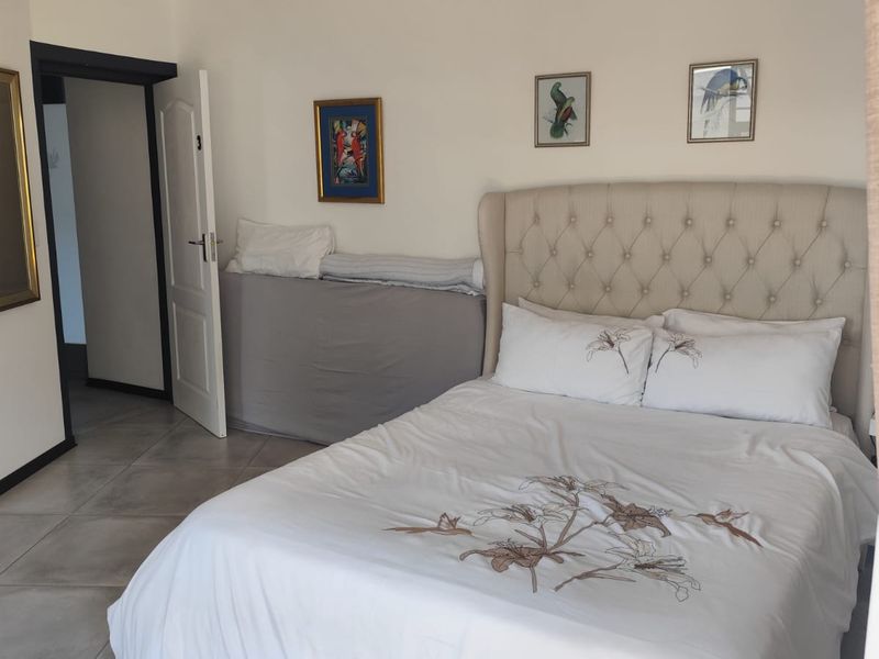 A well-maintained bedroom featuring neutral tiled flooring, recessed ceiling lighting, and a clean, simple layout.