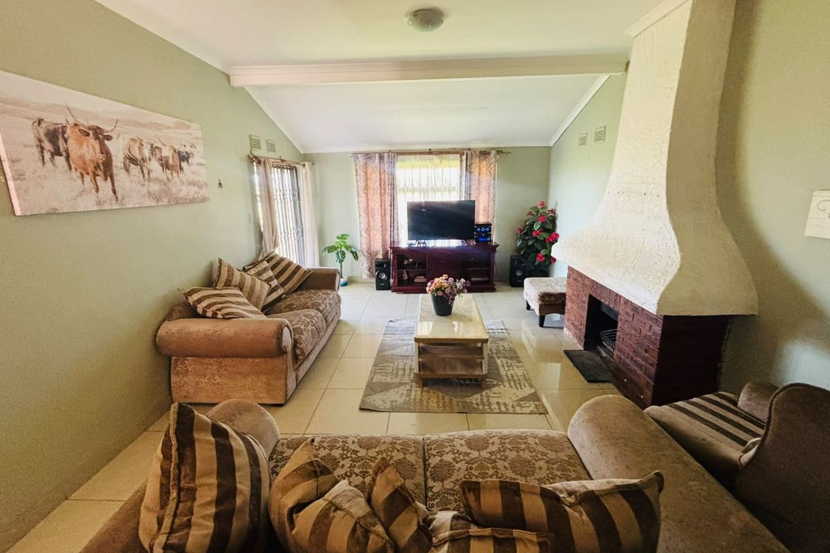 Spacious living room featuring a prominent brick fireplace, tiled flooring, and a vaulted ceiling, offering a comfortable and traditional living space.