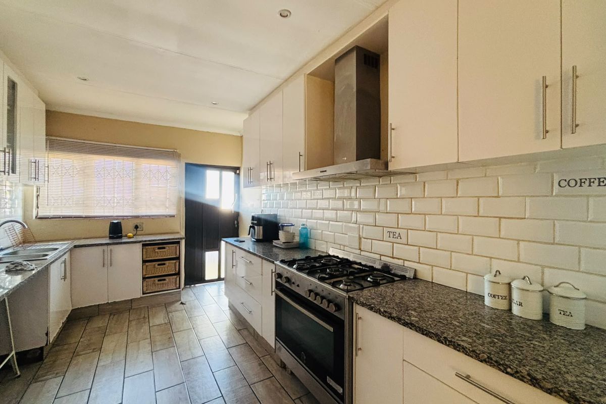 A well-maintained kitchen featuring granite countertops, subway tile backsplash, gas stove with extractor fan, and ample built-in cabinetry.
