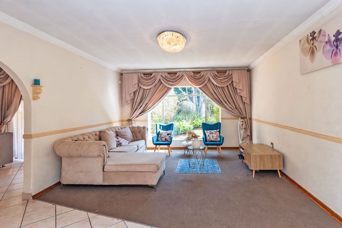 A spacious living room featuring a large window with garden views, decorative ceiling cornice, and chair rail molding.