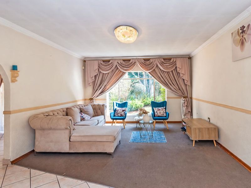 A spacious living room featuring a large window with garden views, decorative ceiling cornice, and chair rail molding.