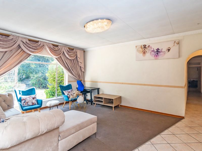 Spacious living room featuring a large picture window, neutral wall finishes, and a combination of tiled and carpeted flooring with an arched entryway.