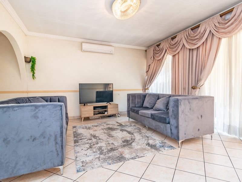 A living room featuring ceramic floor tiles, a split-system air conditioner, and a decorative archway leading to adjacent spaces.