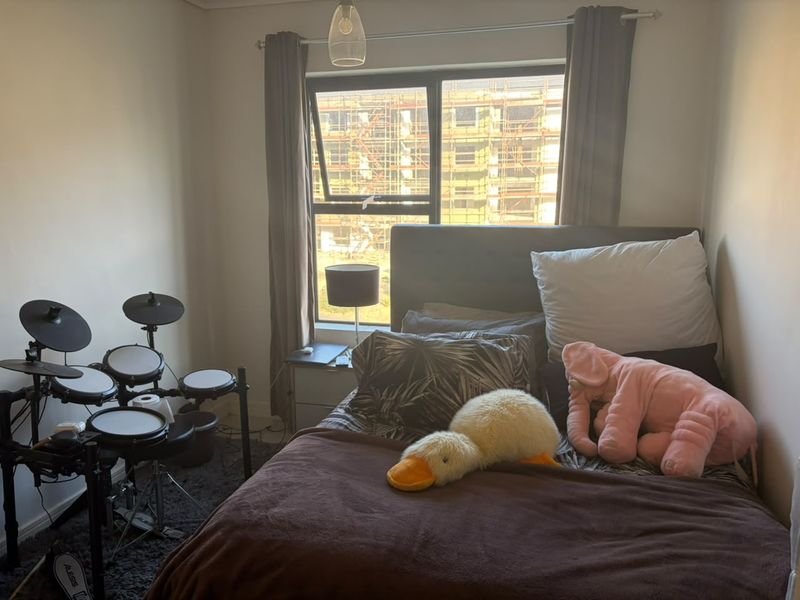 A functional bedroom featuring a window with natural light and neutral wall finishes, suitable for a comfortable sleeping space.