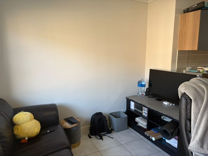 A compact living area featuring tiled flooring and an adjacent kitchen section with built-in cabinetry.