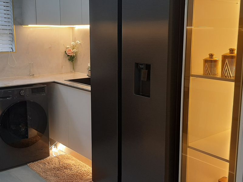 Modern kitchen featuring sleek cabinetry, stone countertops, integrated appliances, and elegant built-in display shelving with ambient lighting.