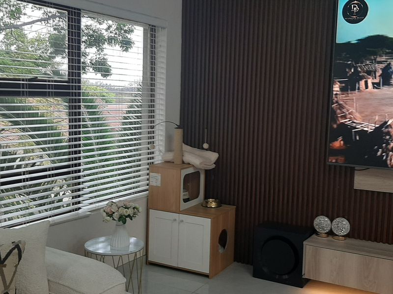 Modern living room featuring stylish slatted wood wall paneling, a floating media console, and large windows with venetian blinds.