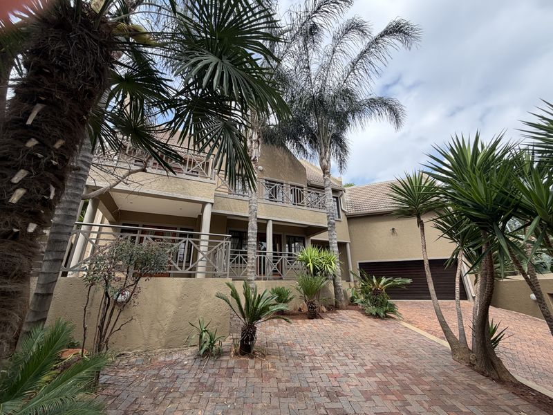 Front elevation of a multi-story cluster home featuring a paved driveway, double garage, and an upper-level balcony with decorative railings.