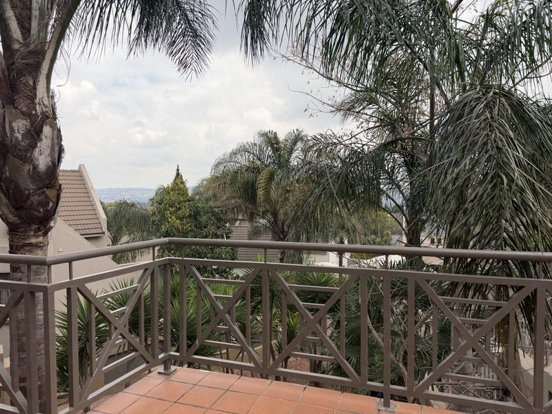 A spacious balcony featuring a durable metal balustrade and tiled flooring, offering pleasant views of the surrounding estate and mature trees.
