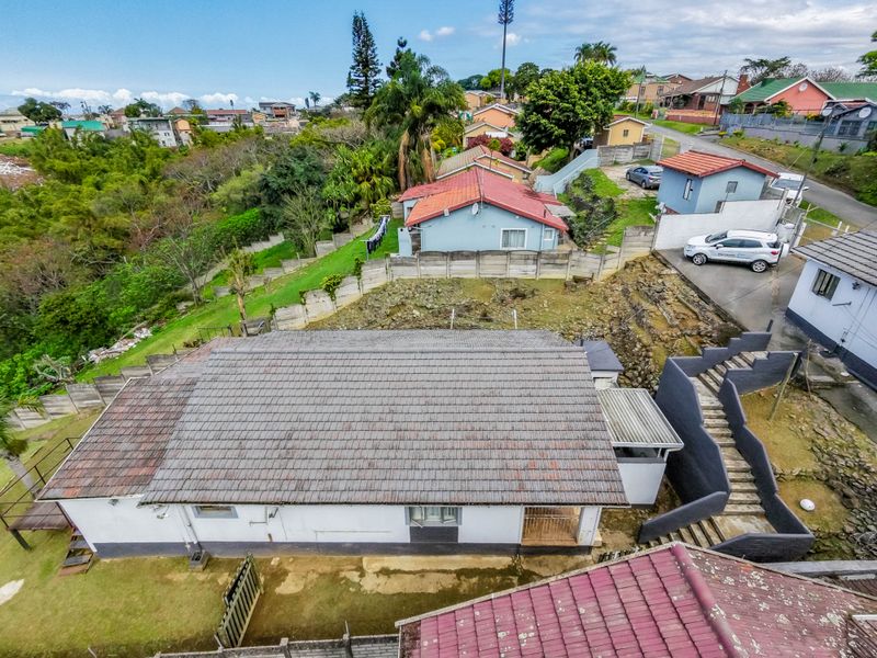 Aerial view of the property showing the roof structure, surrounding garden, concrete retaining walls, and access staircase within a residential neighbourhood setting.