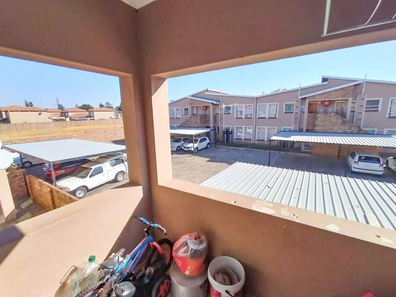 An elevated balcony area overlooking the townhouse complex parking area and carports, providing an open outdoor space.