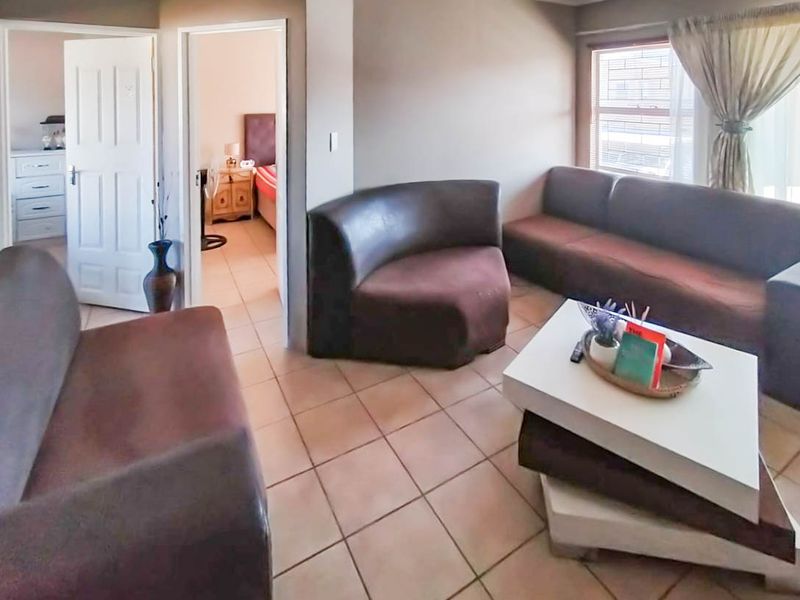 A living room area featuring tiled flooring and coved ceilings, with direct access to adjacent rooms through internal doorways.