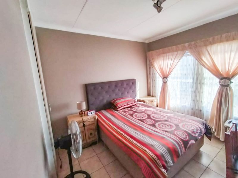 A functional bedroom featuring tiled flooring, a built-in cupboard, and coved ceiling details, offering a comfortable and practical living space.