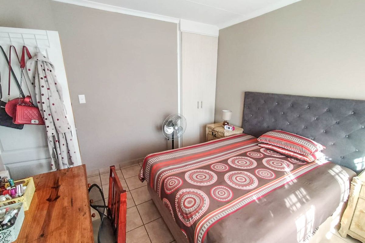 A functional bedroom featuring tiled flooring, neutral wall tones, and a built-in wardrobe, offering a practical space for rest.